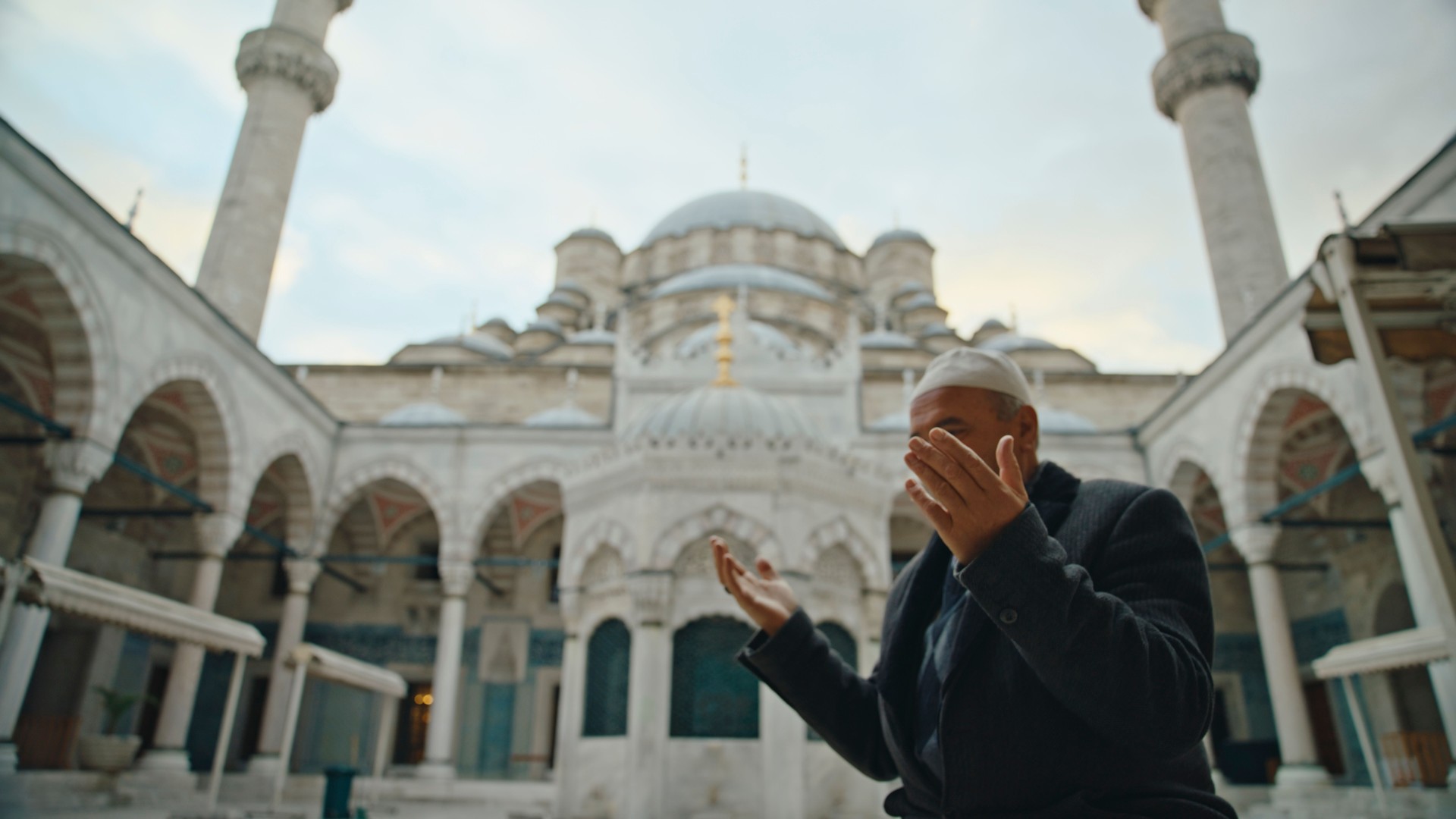 Low Angle View of Mature Man Praying at Courtyard of Blue Mosque against Sky at Istanbul,Turkey Low Angle View of Mature Man Praying at Courtyard of Blue Mosque against Sky at Istanbul,Turkey